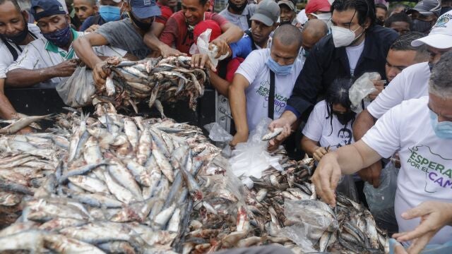 FILE - In this Nov. 4, 2020 file photo, residents help themselves to fish during a campaign rally hosted by ex-presidential candidate Javier Bertucci and Juan Eleazar, both candidates for the upcoming parliamentary elections, at a campaign rally in the Petare neighborhood of Caracas, Venezuela. Both represent the opposition coalition known as "Primero Venezuela," or Venezuela First, ahead of Dec. 6 parliamentary elections. (AP Photo/Ariana Cubillos, File)