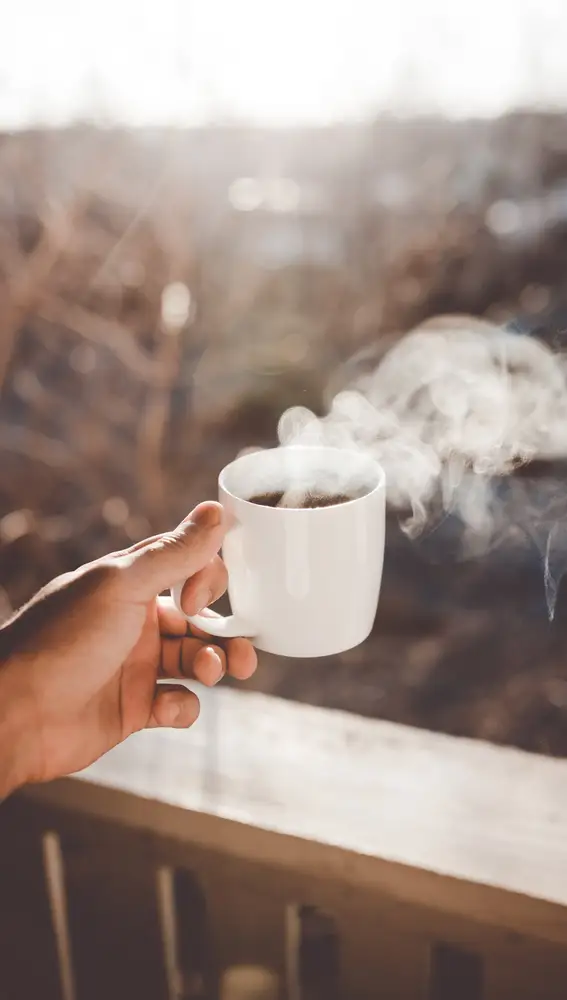 En la imagen, una taza de café humeando en el frío invierno.