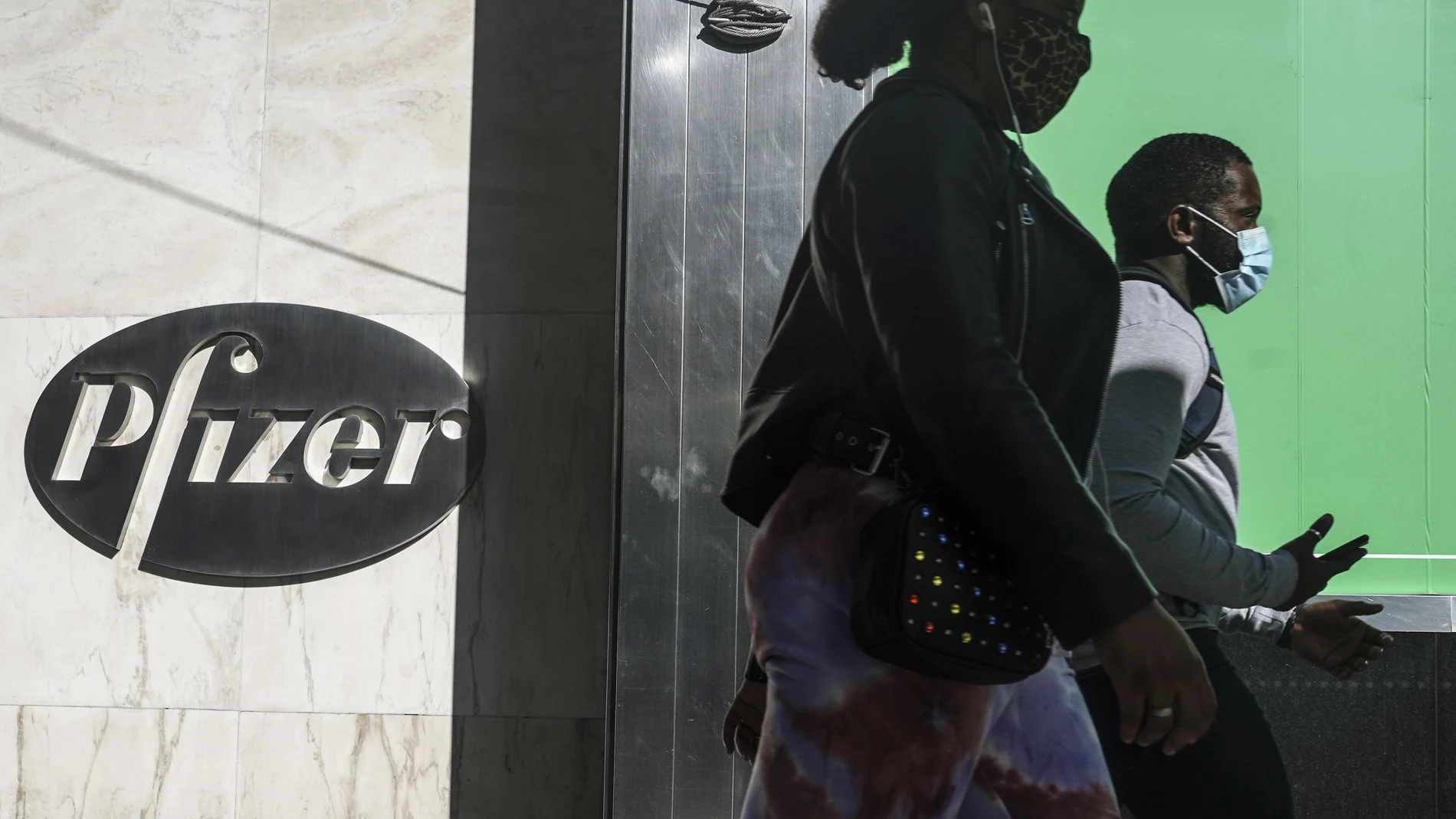 Dos personas caminan junto a las oficinas de Pfizer en Nueva York