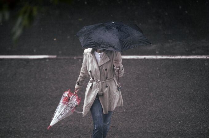 Una persona camina bajo la lluvia protegida con un paraguas, en Madrid