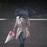 Una persona camina bajo la lluvia protegida con un paraguas, en Madrid