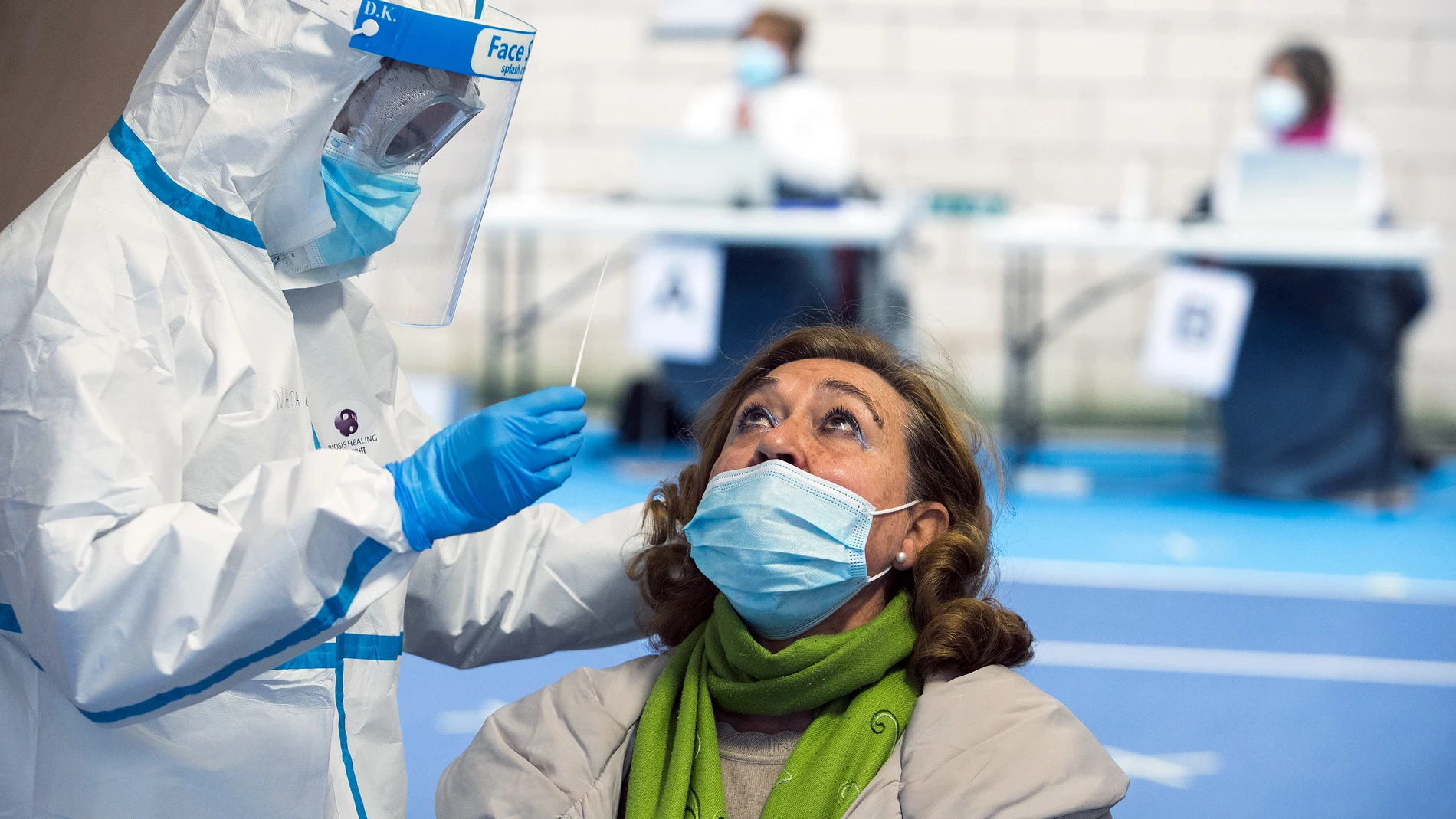 Un trabajador sanitario totalmente protegido realiza un test de antígenos de Covid-19 a una vecina en el Complejo Deportivo El Plantío, en Burgos, Castilla y León, (España), a 21 de noviembre de 2020. La Junta de Castilla y León en colaboración con el Ayuntamiento de la capital ha organizado estos tests masivos de antígenos, que se llevarán a cabo del 21 al 28 de noviembre en las pistas de tenis del complejo deportivo, y serán de carácter voluntario con el fin de detectar la situación epidemiológica real de la ciudad de Burgos, que se está viendo especialmente castigada por la pandemia.21 NOVIEMBRE 2020;PANDEMIA;BURGOS;COVID19;TEST ANTIGENOSTomás Alonso / Europa Press21/11/2020