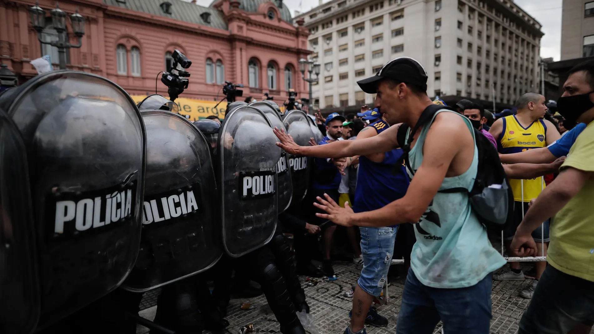 Un grupo de personas choca con la policía durante la espera para poder ingresar al velatorio de Diego Armando Maradona, hoy jueves en la Plaza de Mayo de Buenos Aires