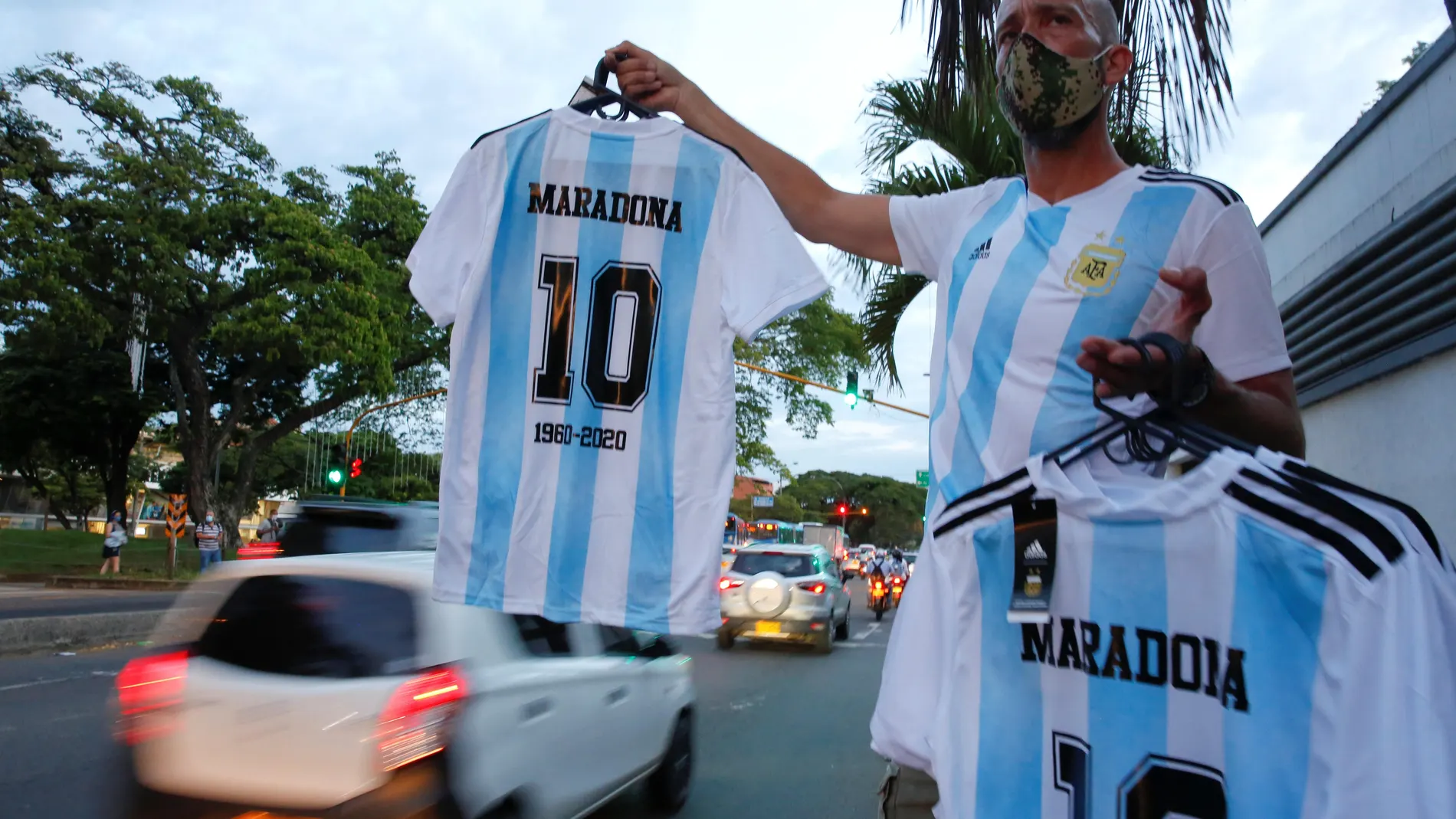 Un hombre vende camisetas del exfutbolista Diego Armando Maradona en una calle, hoy en Cali (Colombia).