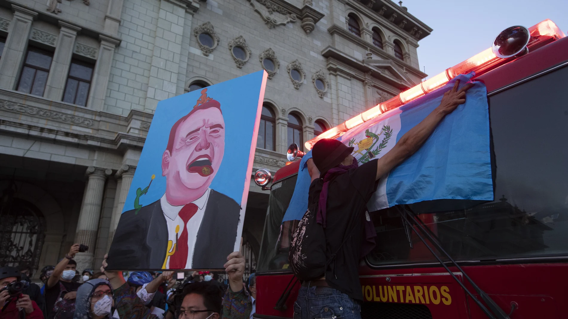 A protester holds up a painting depicting President Alejandro Giammattei during a protest demanding his resignation, in Guatemala City, Saturday, Nov. 28, 2020. Protests continue against Giammattei and the legislature for approving a budget that cut educational and health spending. Guatemala's Congress backed down on Monday on the proposed federal budget. (AP Photo/Moises Castillo)