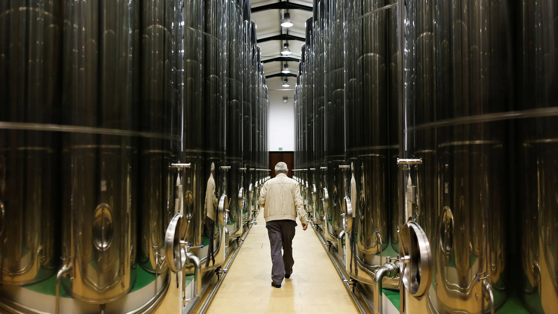 Un hombre camina entre las almazaras de una cooperativa de producción de aceite en Porcuna