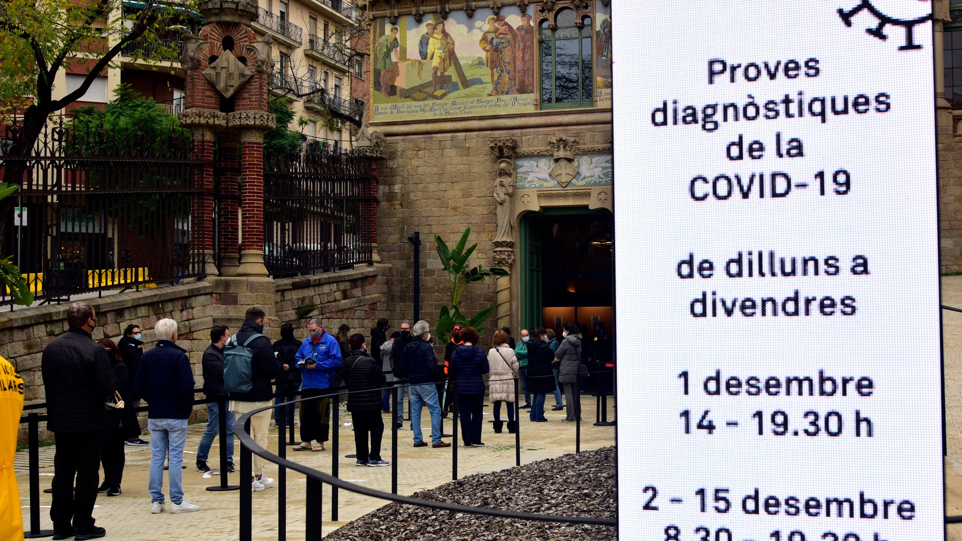 Varias personas hacen cola para realizarse test a la entrada del Recinto Modernista del Hospital de Sant Pau de Barcelona