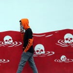 Una joven iraní pasa junto a un mural anti estadounidense en Teherán