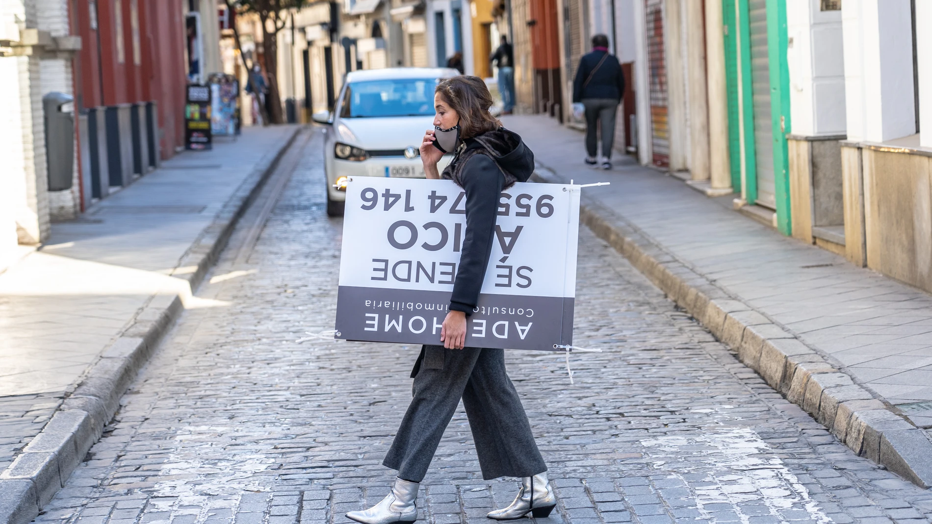 Una mujer con un cartel de compra venta de vivienda por los alrededores de la Catedral de Sevilla. Eduardo Briones / Europa Press