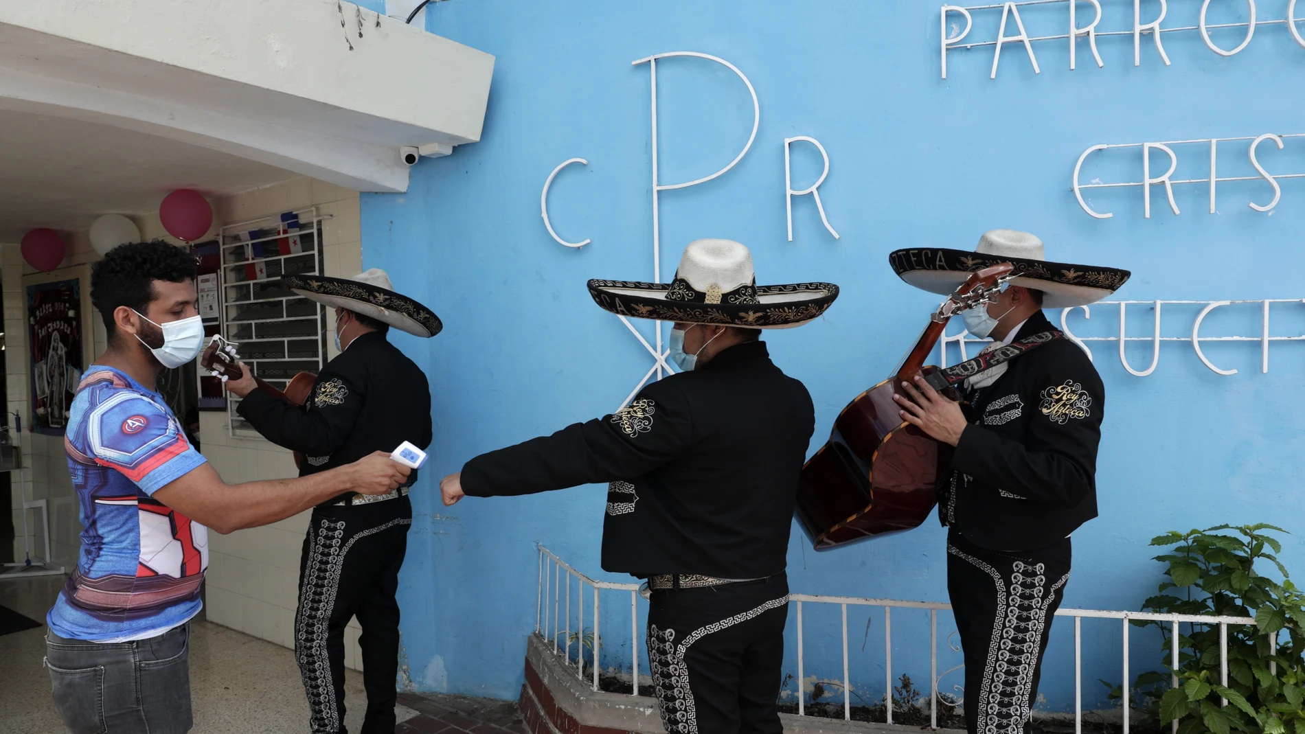 Mariachi band players wearing masks to curb the spread of the new coronavirus have their temperature taken before a Mother's Day performance at the Cristo Resucitado Church in Panama City, Tuesday, Dec. 8, 2020. Panamanian health authorities announced the extension of the night curfew hours in Panama City to face a rebound in coronavirus cases. (AP Photo/Arnulfo Franco)