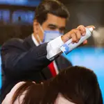 El presidente Nicolás Maduro usa espray desinfectante tras una rueda de prensa