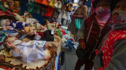 BOL01. LA PAZ (BOLIVIA), 09/12/2020.- Fotografía de imágenes del niño Jesús en un puesto de la feria navideña, el 7 de diciembre de 2020, en La Paz (Bolivia). Las pequeñas figuras de estuco hechas a mano en los talleres artesanales de La Paz para el Belén o pesebres navideños son vestidos con tapabocas y traje de bioseguridad, toda una actualización de la teología popular que se han acomodado a los nuevos tiempos, en este caso a la pandemia que también afecta a Bolivia ante la alerta de un rebrote, tras cerca de 9.000 fallecidos y unas 145.000 infecciones desde marzo pasado. EFE/ Martin Alipaz