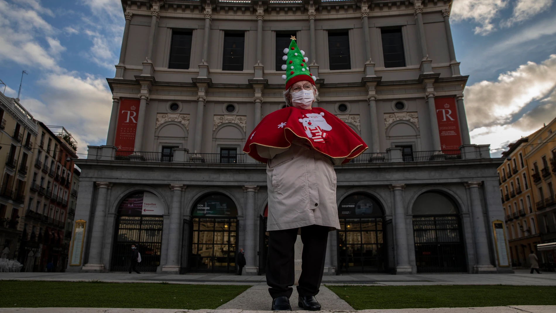 Manoli Sevilla, de 82 años, posa en el teatro real con una capa roja y un árbol de navidad como sombrero