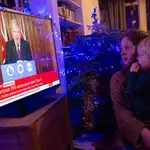 Dos británicos observan la comparecencia del primer ministro Boris Johnson esta tarde en la BBC anunciando más restricciones esta Navidad