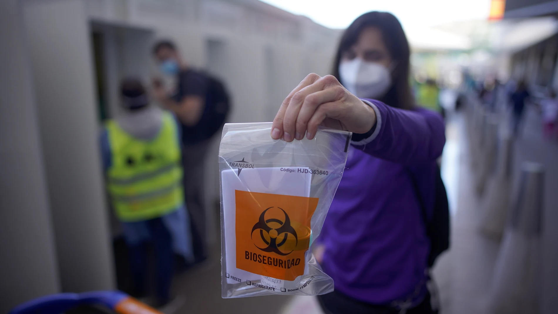 Un argentino muestra una bolsa de plástico con una muestra de saliva para una prueba de covid-19