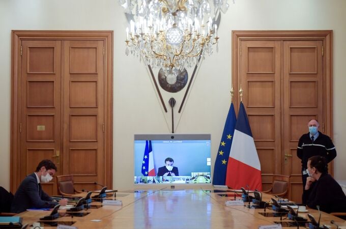 France's President Emmanuel Macron, who tested positive for the coronavirus disease (COVID-19), is seen on a screen as he attends by video conference a round table for the weekly cabinet meeting of the government at the Army Ministry in Paris, France, December 21, 2020. Julien De Rosa/Pool via REUTERS