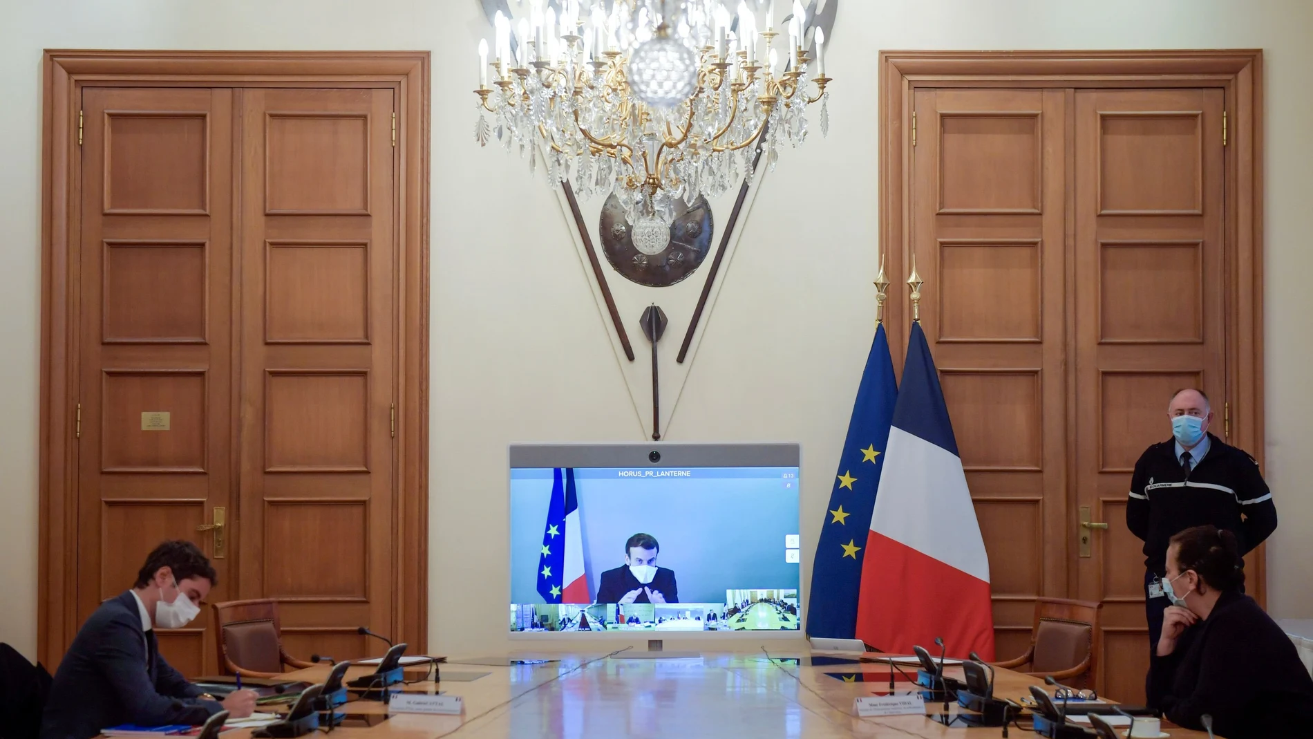France's President Emmanuel Macron, who tested positive for the coronavirus disease (COVID-19), is seen on a screen as he attends by video conference a round table for the weekly cabinet meeting of the government at the Army Ministry in Paris, France, December 21, 2020. Julien De Rosa/Pool via REUTERS