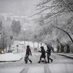 Heavy snow falls as people wearing face masks to curb the spread of COVID-19 crosses a road in Burnaby, British Columbia, on Monday, Dec. 21, 2020. Environment Canada issued a snowfall warning on the first day of winter. (Darryl Dyck/The Canadian Press via AP)