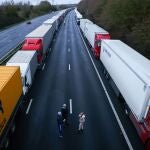 Tres conductores toman bebidas calientes mientras están parados junto a los camiones estacionados en la autopista M20, cerca de Ashford, Gran Bretaña