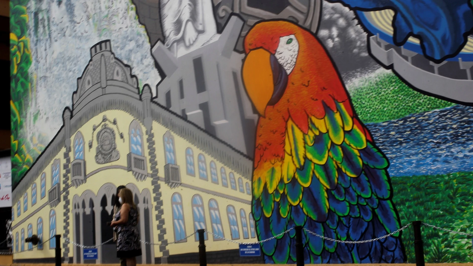 AME6263. TEGUCIGALPA (HONDURAS), 22/12/2020.- Dos mujeres caminan frente a un mural que destaca el turismo en Honduras, hoy en Tegucigalpa. EFE/Gustavo Amador
