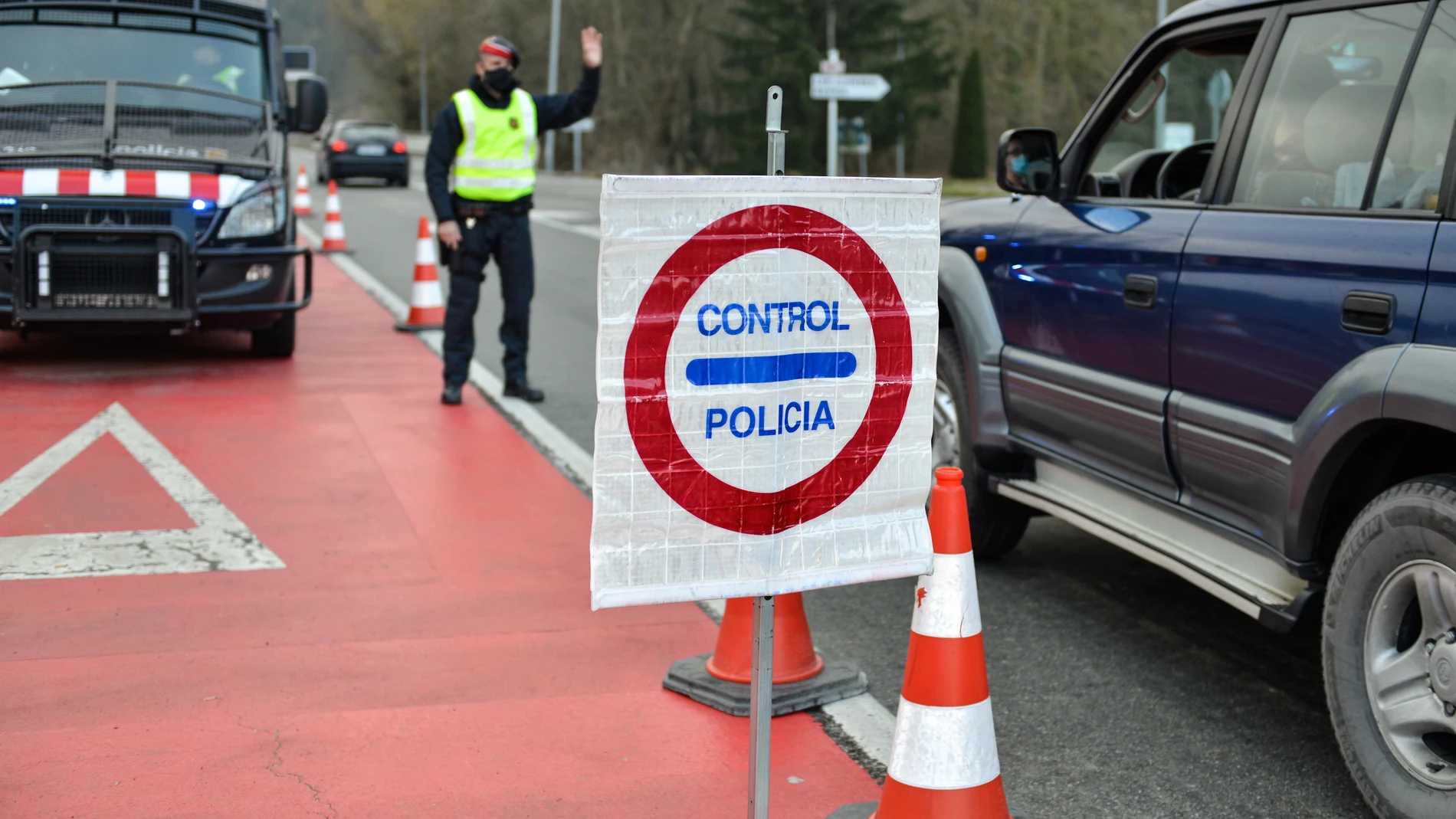 Un Mosso d'Esquadra para a un coche durante el control policial por el confinamiento perimetral en la C-17 a la entrada de Ripoll, en Girona.
