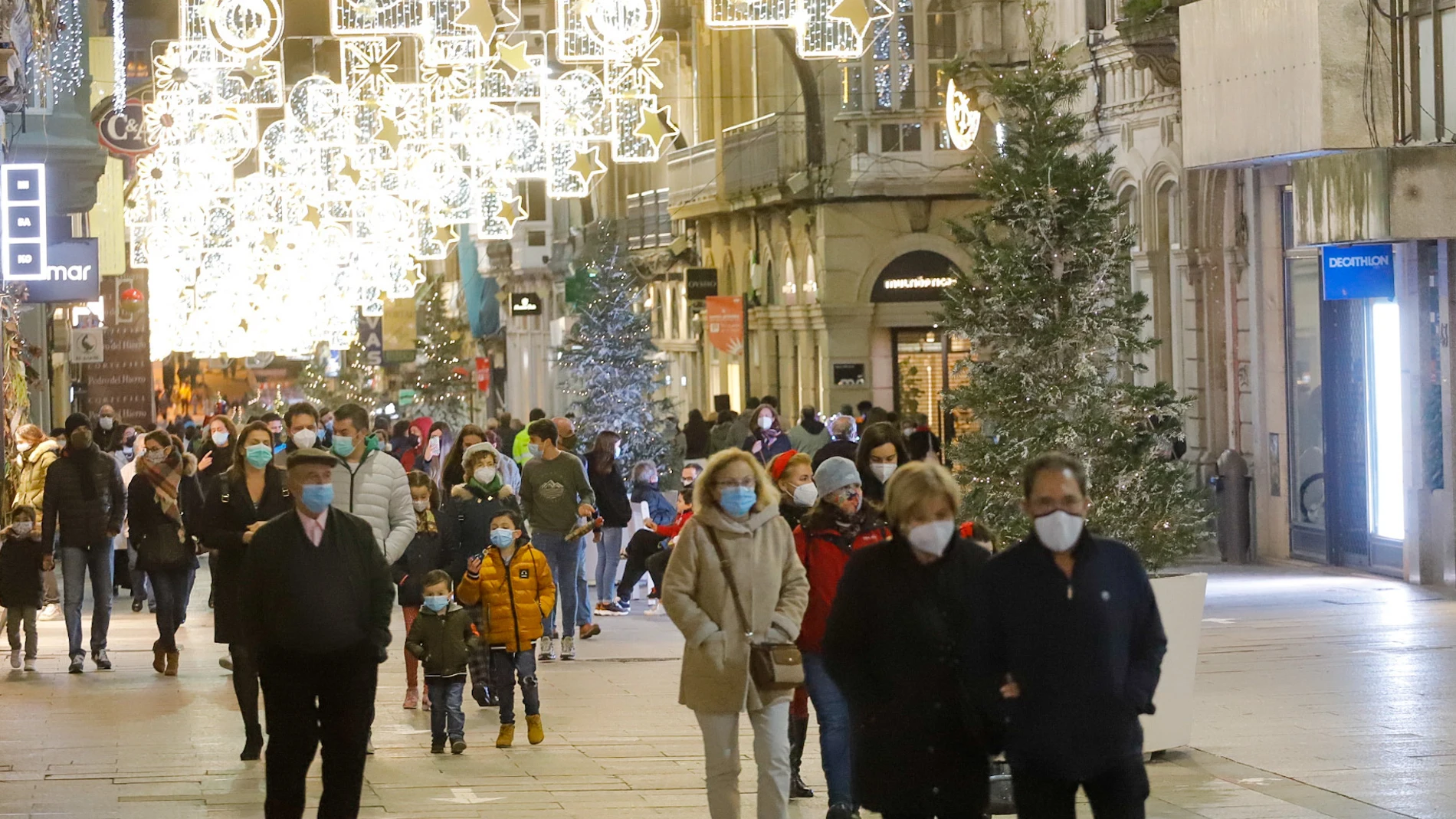 Transeúntes pasean bajo las luces navideñas, llevando mascarilla, en Vigo, Galicia (España), a 25 de diciembre de 2020