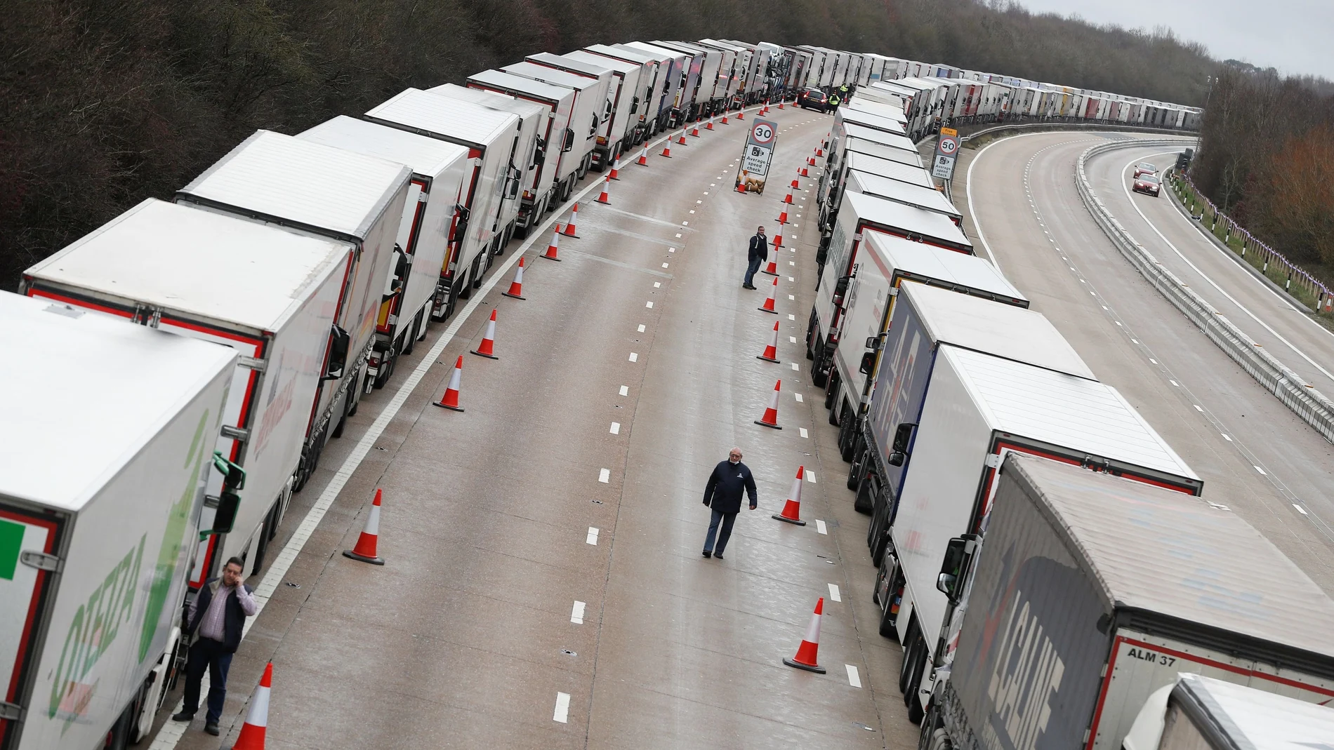People walk amid lines of lorries queueing at the M20 motorway near Ashford amid the coronavirus disease (COVID-19) outbreak, Britain, December 26, 2020. REUTERS/Peter Nicholls