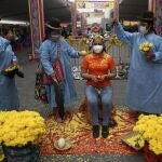 Shamans use flowers and food to perform a cleansing ritual for Brigite Garces for about a $10 dollar fee at the "Mercado de Deseos," or Market of Wishes which sets up for one week in Lima, Peru, Monday, Dec. 28, 2020. Amid the COVID-19 pandemic this year, people are wishing for good health and work in 2021, as many have been left without either. (AP Photo/Martin Mejia)