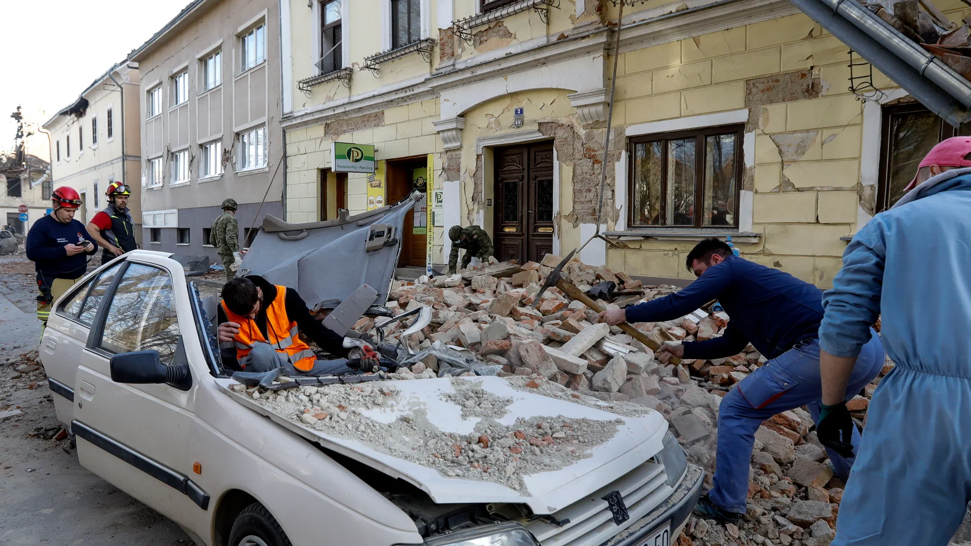 Petrinja (Croatia), 29/12/2020.- People and soldiers clean the rubble next to car and buildings damaged in an earthquake in Petrinja, Croatia, 29 December 2020. A 6.4 magnitude earthquake struck around 3km west south west of the town with reports of many injuries and at least one death. (Terremoto/sismo, Croacia) EFE/EPA/ANTONIO BAT