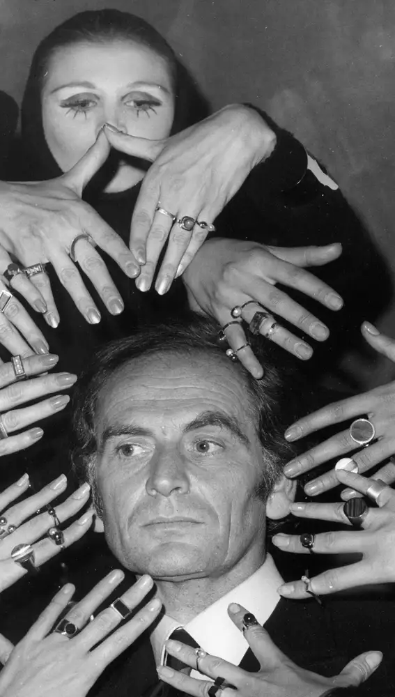 FILE - In this Sept. 19, 1969 file photo, French fashion designer Pierre Cardin's face is framed by 10 hands of models like a sculptur of goddess Siva ornamented with a collection of rings designed by Cardin from his latest jewelery collection, in Paris, France.France's Academy of Fine Arts says Pierre Cardin, the French designer whose Space Age style was among the iconic looks of 20th-century fashion, has died at 98.(AP Photo, File)