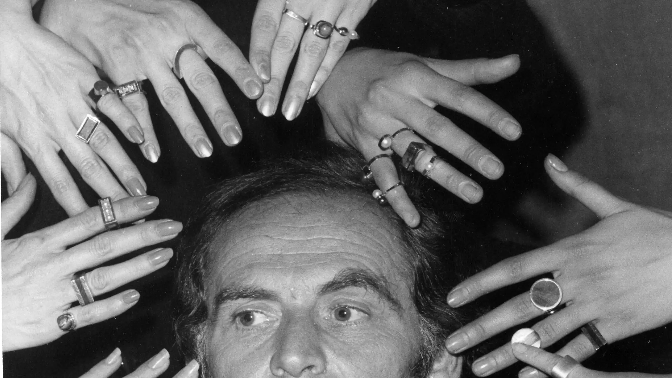 FILE - In this Sept. 19, 1969 file photo, French fashion designer Pierre Cardin's face is framed by 10 hands of models like a sculptur of goddess Siva ornamented with a collection of rings designed by Cardin from his latest jewelery collection, in Paris, France.France's Academy of Fine Arts says Pierre Cardin, the French designer whose Space Age style was among the iconic looks of 20th-century fashion, has died at 98.(AP Photo, File)
