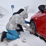 Una pareja pone las cadenas a las ruedas de su coche en una carretera del Pirineo aragonés