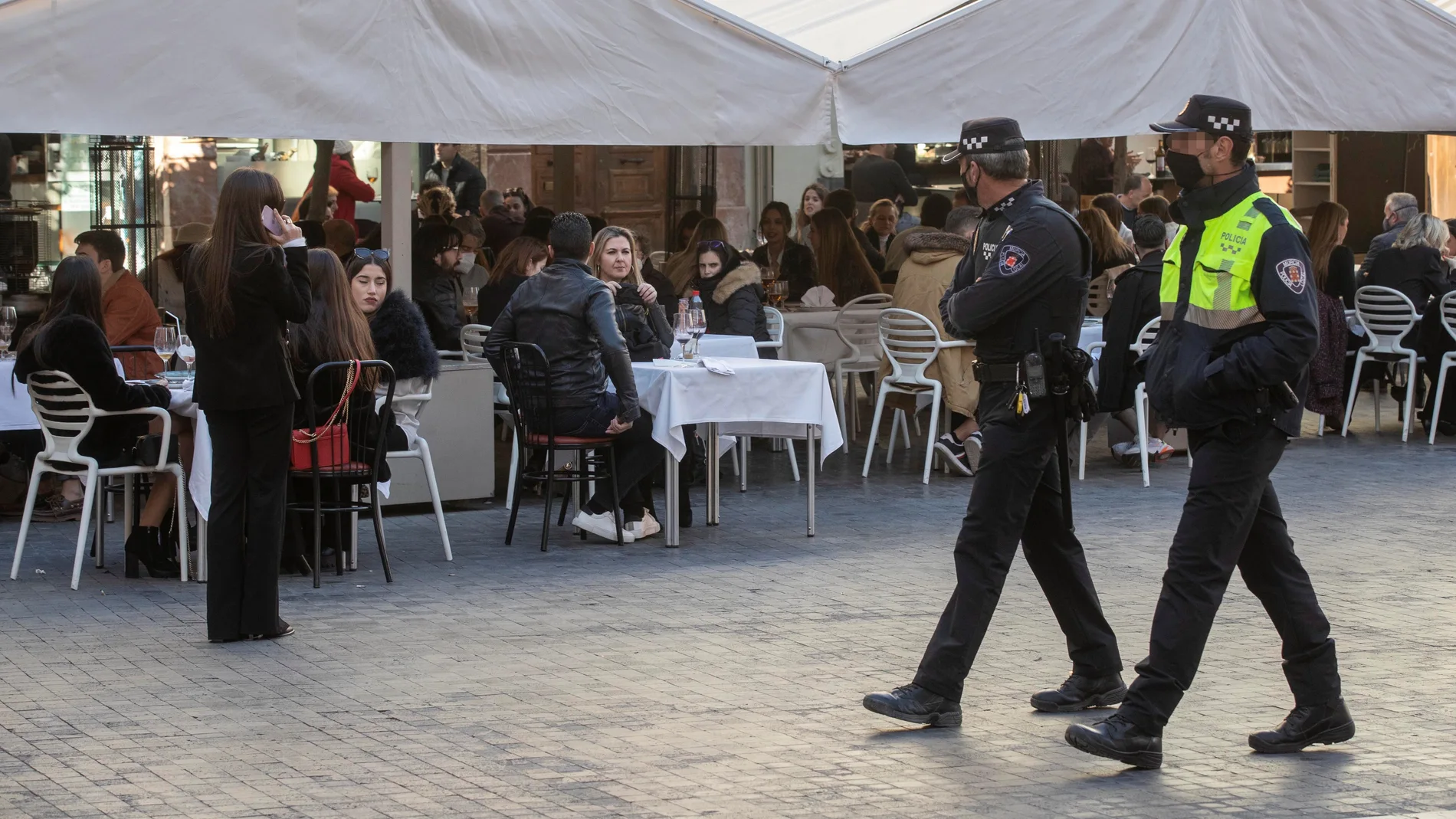 Dos policías locales vigilan el aforo de la terraza de un resturante de la Plaza del Cardenal Belluga de Murcia, este jueves día de nochevieja