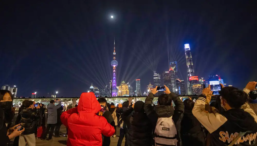 Shanghai (China), 31/12/2020.- People take pictures from The Bund waterfront area of the Peal Tower landmark and a light show during New Year's Eve celebrations in Shanghai, China, 31 December 2020. EFE/EPA/ALEX PLAVEVSKI