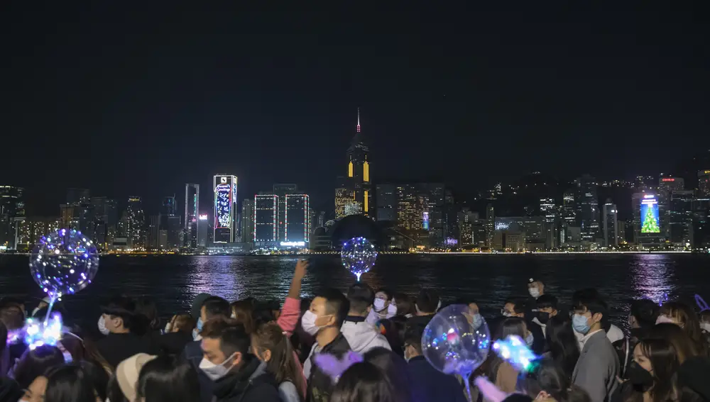 People walk at the waterfront of the Victoria Harbor to celebrate the New Year's Eve of year 2021, in Hong Kong, Thursday, Dec. 31, 2020. The harbor would normally be very busy with light displays and fireworks to celebrate New Year. (AP Photo/Kin Cheung)