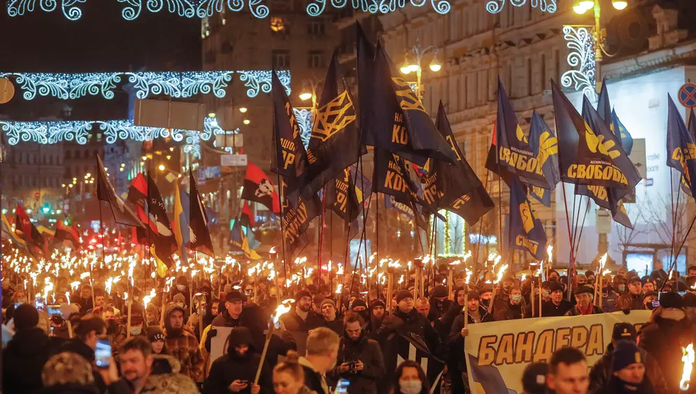 Personas con antorchas y banderas nacionalistas del partido político ultranacionalista de extrema derecha Svoboda durante un mitin de varios partidos nacionalistas para conmemorar el 112 cumpleaños de Stepan Bandera, en Kiev, Ucrania, en enero de 2021