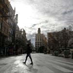 La ciudad de Valencia ha entrado con un ritmo pausado en el año 2021. En la imagen un joven cruza, este viernes al mediodía, una inusualmente tranquila plaza del Ayuntamiento de Valencia. EFE/Manuel Bruque
