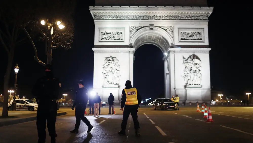 Police officers stand on the Champs Elysees avenue next to the Arc of Triomphe as they control cars during the New Year's Eve, in Paris, Thursday, Dec. 31, 2020. As the world says goodbye to 2020, there will be countdowns and live performances, but no massed jubilant crowds in traditional gathering spots like the Champs Elysees in Paris and New York City's Times Square this New Year's Eve. (AP Photo/Thibault Camus)
