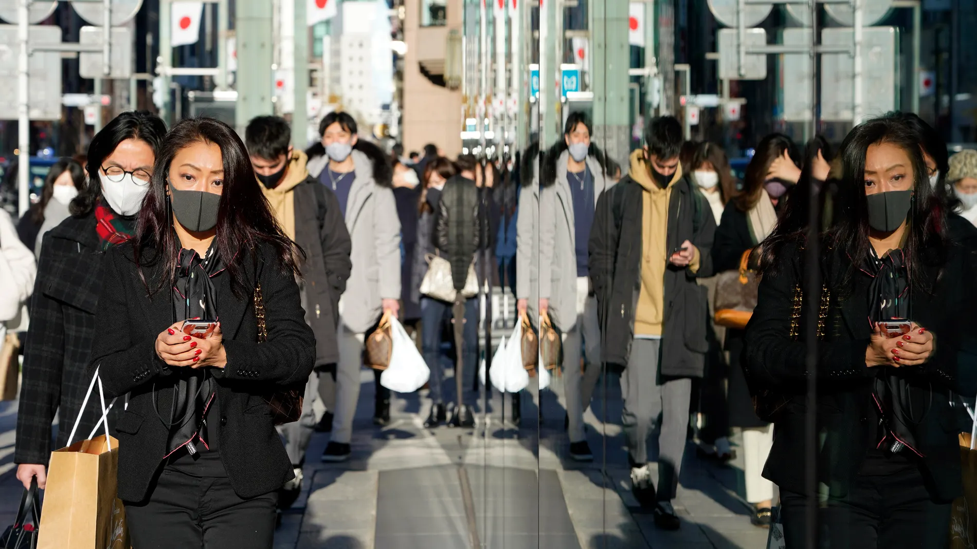 Tokyo (Japan), 02/01/2021.- Passersby wearing protective face masks are reflected in a show window at Ginza shopping district in Tokyo, Japan, 02 January 2021. The Tokyo Metropolitan Government announced that it has confirmed that 814 new people have been infected with the coronavirus in Tokyo. Following the surge in cases number, Tokyo and three surrounding prefectures are expected to ask the central government to declare a state of emergency. (Japón, Tokio) EFE/EPA/FRANCK ROBICHON