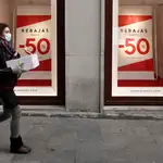 Una mujer pasa frente a un escaparate que anuncia las rebajas en el centro de Madrid, este lunes