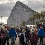 Backdropped by the Gibraltar rock, people walk along the stalls of a weekly market at the Spanish city of La Linea on Monday, Jan. 4, 2021. Fears of disruptions following Britain's departure from the European Union were replaced by coronavirus-related restrictions on border traffic between Spain and Gibraltar on Monday, the first working day at the United Kingdom's only land border with the European mainland. (AP Photo/Emilio Morenatti)