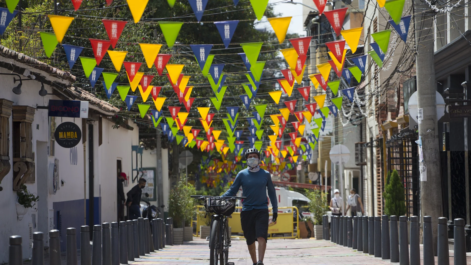 A cyclist wearing a protective face mask amid the new coronavirus pandemic, pushes his bike along a pedestrian path in Bogota, Colombia, Tuesday, Jan. 5, 2021. Colombia's capital city is reimposing lockdown measures on Tuesday as COVID-19 infections rise around the country. (AP Photo/Ivan Valencia)