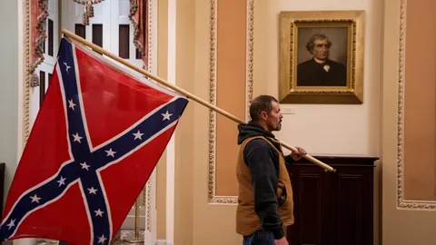 Uno de los seguidores de Donald Trump que irrumpieron en el Capitolio y que pasa por delante de uno de los retratos que se conservan en su interior