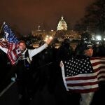Los partidarios de Trump, con banderas estadounidenses, caminan junto a la policía cerca del Capitolio de EE UU