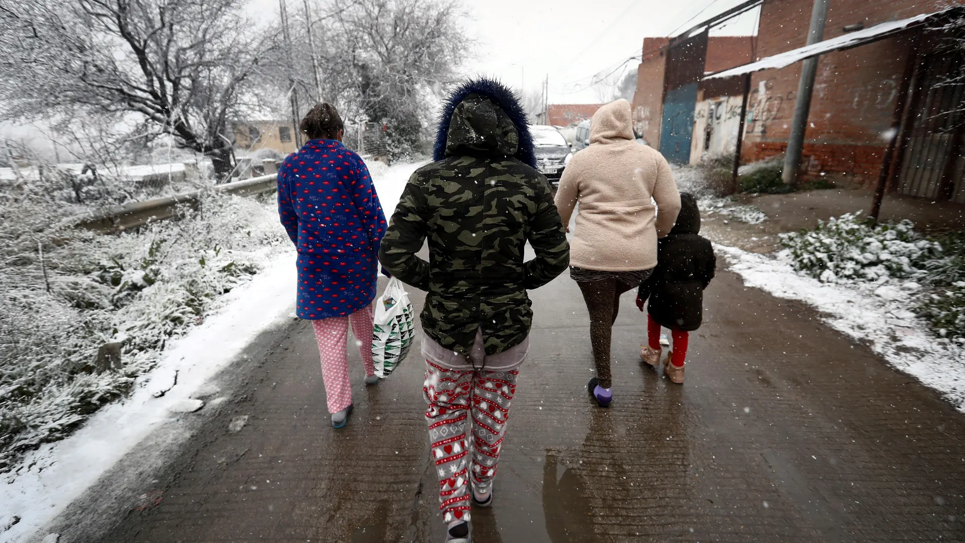 Varios residentes del asentamiento de la Cañada Real caminan bajo la nieve este jueves 7 de enero.