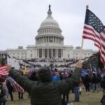 Un seguidor de Donald Trump sostiene la bandera de los Estados Unidos frente al Capitolio