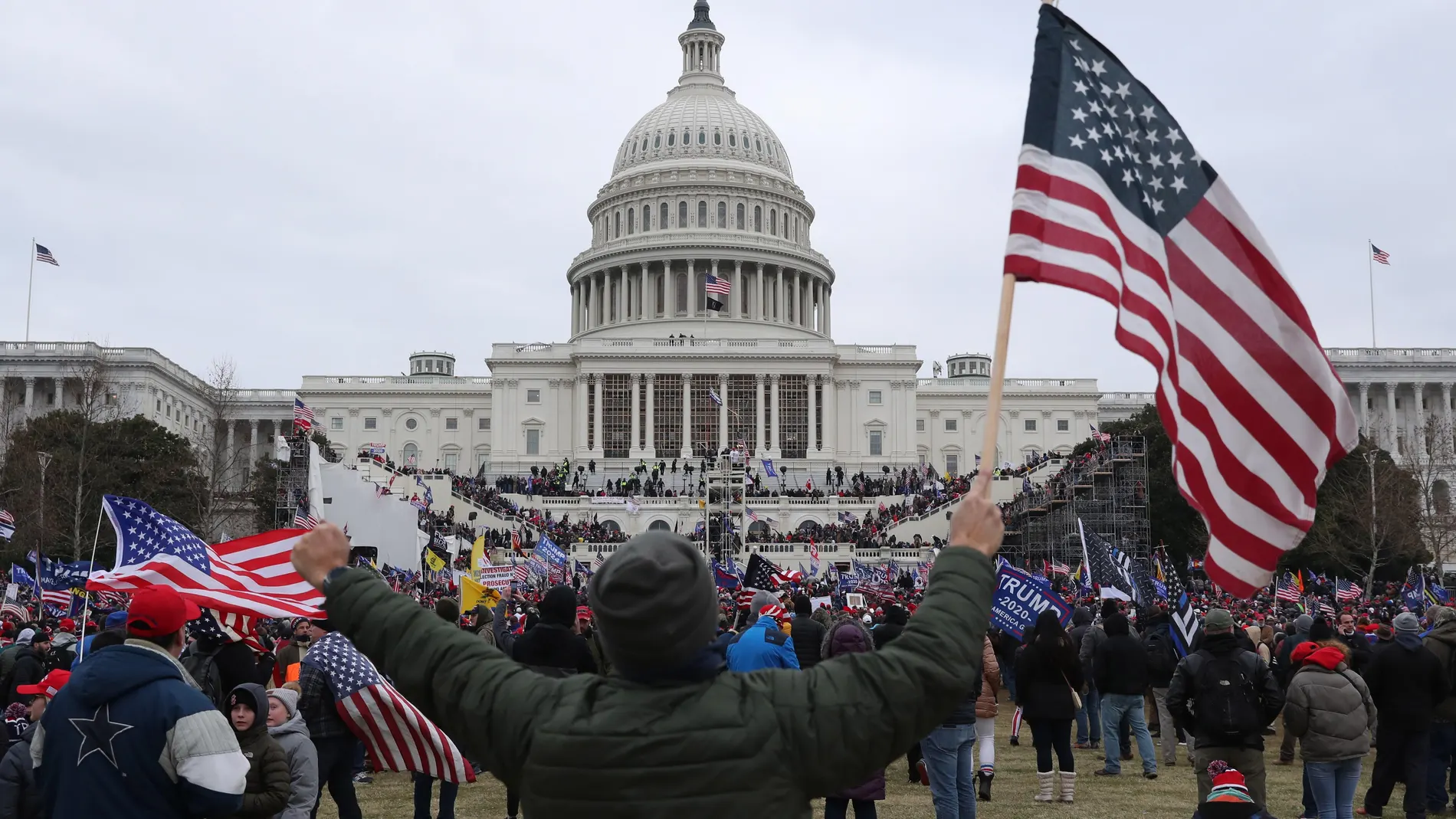 Un seguidor de Donald Trump sostiene la bandera de los Estados Unidos frente al Capitolio