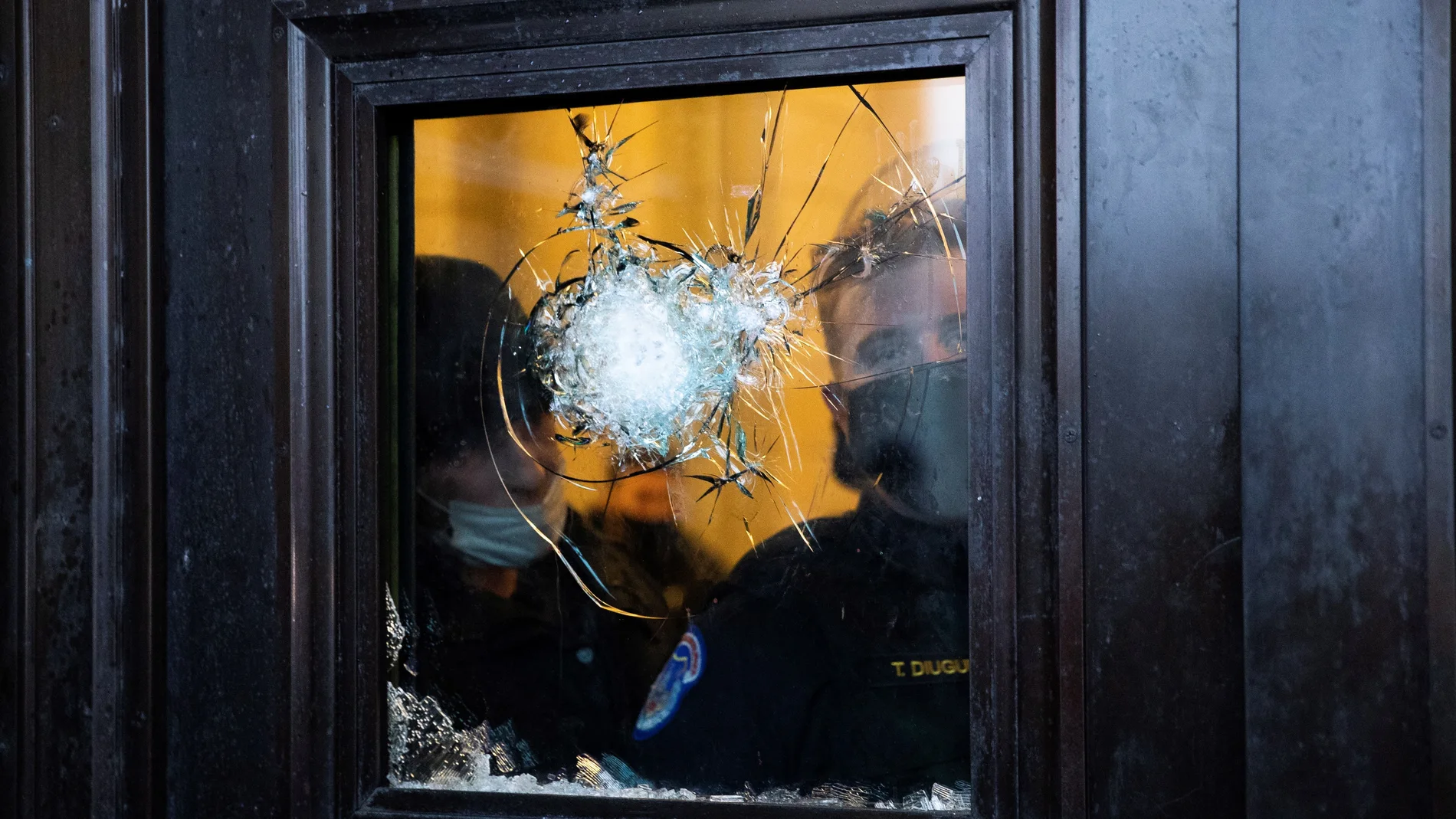 Dos policías observan a través del vidrio roto de una de las puertas del Capitolio de Estados Unidos, luego de que seguidores de Donald Trump irrumpieran en el recinto durante unas protestas en Washington (Estados Unidos).