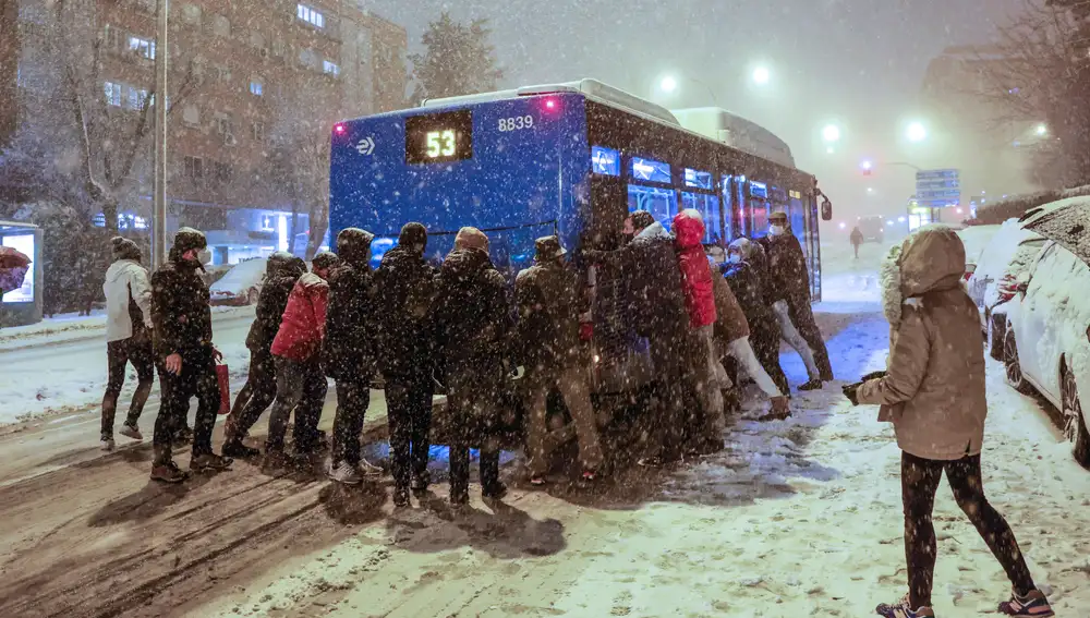 Varias personas empujan un autobús bajo una intensa nevada en la avenida Ramón y Cajal