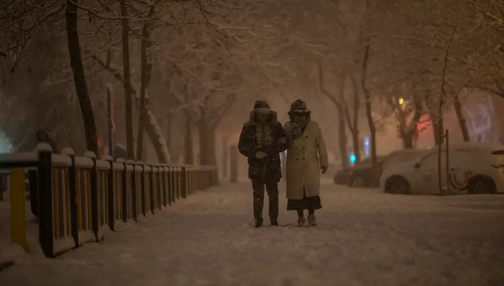 Una pareja pasea bajo la nieve en Madrid